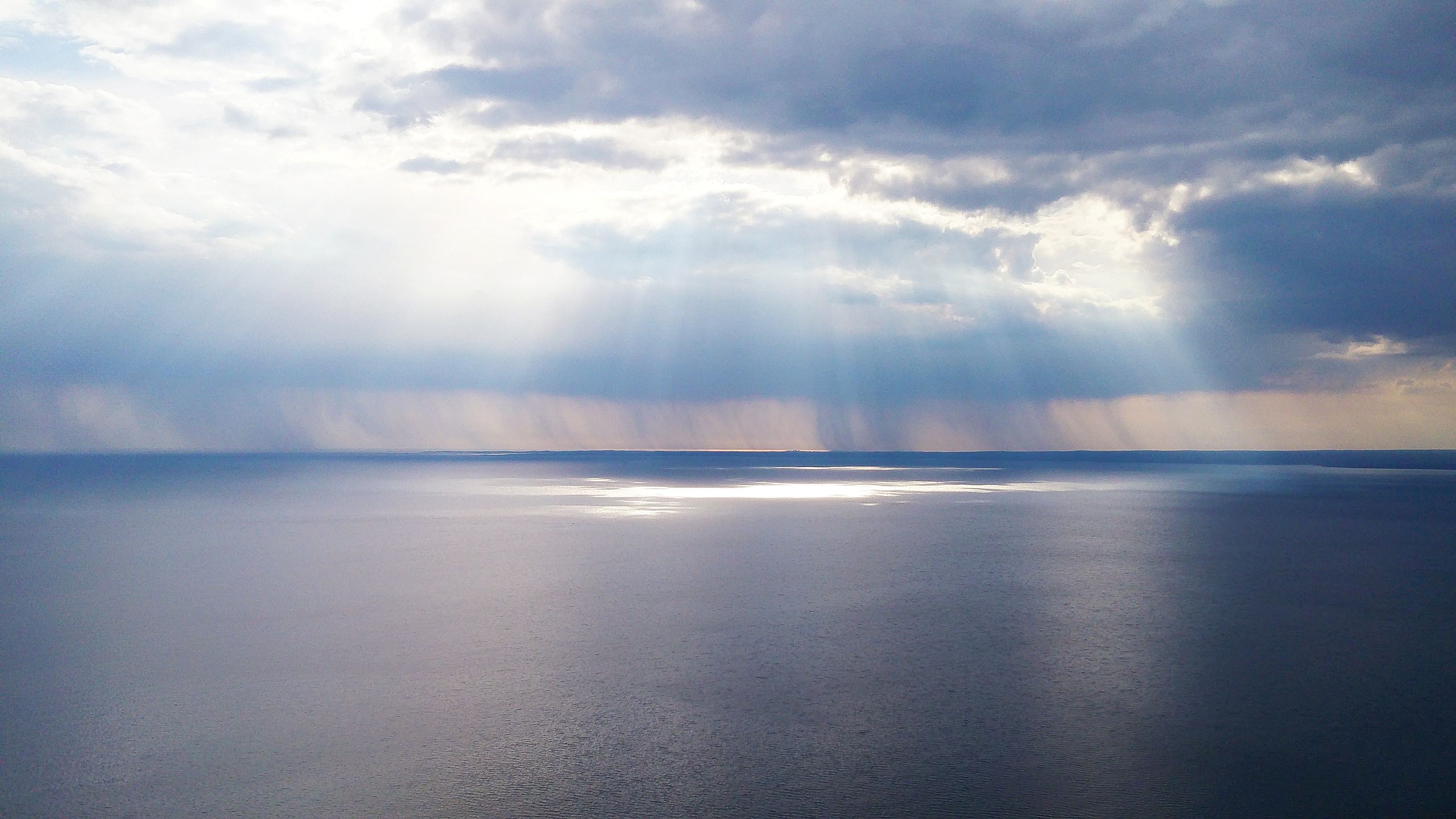 Captivating ocean view with sunrays breaking through clouds, creating a serene and calming effect.